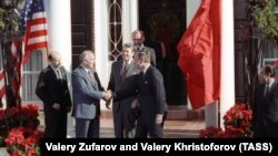 Генералният секретар на комунистическата партия на СССР Михаил Горбачов се ръкува с вицепрезидента на САЩ Джордж Буш. До тях е президентът Роналд Рейгън. Снимката е направена преди началото на среща в Ню Йорк през декември 1988 г.