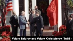 Udhëheqësi sovjetik Mikhail Gorbachev (i dyti nga e majta) shtrëngon duart me nënpresidentin, George Bush, ndërsa presidenti Ronald Reagan qëndron pas tyre para bisedimeve në Nju Jork në dhjetor të vitit 1988.