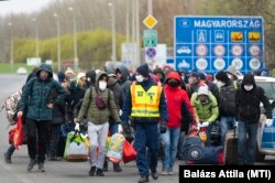 A járvány miatt hazautazó ukrán állampolgárok egy csoportját kíséri egy rendőr a záhonyi határátkelőhelyen 2020. március 30-án