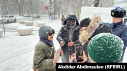 Активистка Акторгын Аккенжебаласы разговаривает с представителям власти, который прерывает ее пикет в Алматы. 22 января 2025 года