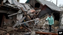 A woman stands near the debris of her house following Russian shelling in the Donetsk region on December 
