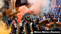 A Momentum képviselői a szavazás előtt tiltakozásul piros-fehér-zöld füsttel borították be az üléstermet 2025. március 18-án