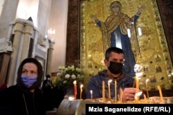 მორწმინეები სანთელს ანთებენ და ლოცულობენ სამების საკათედრო ტაძარში.