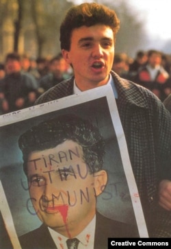 ახალგაზრდა მომიტინგე, რომელსაც ხელში უჭირავს ჩამოგდებული დიქტატორის ნიკოლაე ჩაუშესკუს პორტრეტი. ბუქარესტი, 1989 წლის დეკემბერი