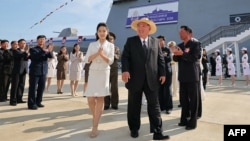 Ким Чен Ын и его дочь Чжу Э (рядом слева) на церемонии второго спуска на воду эсминца "Кан Кон" в порту города Расон. Этот эсминец в результате неудачного спуска месяцем ранее был поврежден, и потом успешно спущен на воду лишь со второй попытки. 12 июня 2025 года