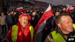 Suporteri ai candidatului PiS Nawrocki, unul dintre ei purtând chipiul „Make America Great Again”, urmăresc din stradă dezbaterea de la Końskie.