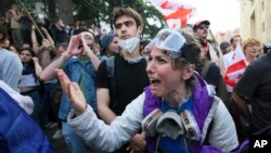 Un protestatar se ceartă cu ofițerii de poliție în timpul unui protest al opoziției împotriva legii „agentului străin” în fața clădirii parlamentului din Tbilisi, pe 28 mai.