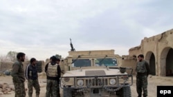 Members of the Afghan security forces stand around a lightly armored vehicle during an operation against Taliban fighters in Helmand, December 2015.