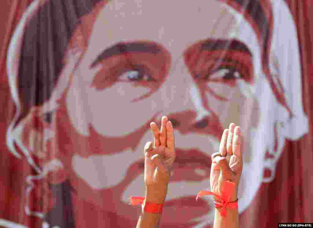 Demonstranti pozdravljaju s tri prsta pored portreta privedene državne savjetnice u Mjanmaru Aung San Suu Kyi tokom protesta protiv vojnog puča, u Jangonu, 9. februara 2021. godine.