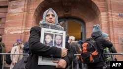 Сирийката Ясмин ал-Машан държи снимки на своите братя пред съда в Кобленц. Четирима от тях са жертви на сирийския режим.