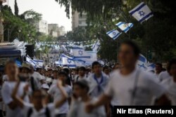Tineri fluturând steaguri israeliene în timpul unei parade care marchează Ziua Ierusalimului, pe fondul tensiunii israeliano-palestiniene, la Ierusalim, 10 mai 2021.