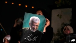 Un susținător al lui Saeed Jalili, candidat la alegerile prezidențiale din 28 iunie, ține afișul său în timpul unei adunări de campanie în Teheran, Iran, miercuri, 26 iunie 2024.