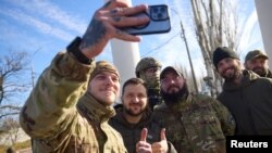 Președintele ucrainean Volodimir Zelenski alături de soldați, în timpul unei vizite în Hersonul recent eliberat, 14 noiembrie 2022