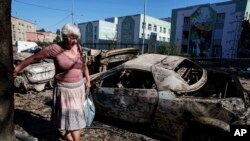 Një grua duke ecur pranë veturave të shkatërruara pas një sulmi rus në Kiev, më 4 korrik 2025.