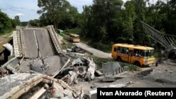 Un convoi cu refugiați din orașul Kupiansk, ocupat de trupele rusești, pe un drum avariat la periferia orașului Harkov, 30 mai 2022