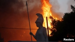 Статуата на божицата Атена во селото Варибоби, 30 километри северозападно од Атина кое што е зафатено од пожар, 03.08.2021
