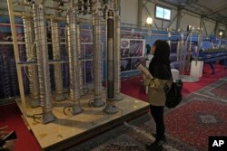 O studentă privește centrifugele construite în Iran într-o expoziție din Teheran, 8 februarie 2023.