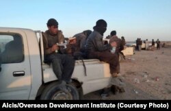 Afghans being smuggled sit atop pickup trucks from Zaranj in Nimroz Province.