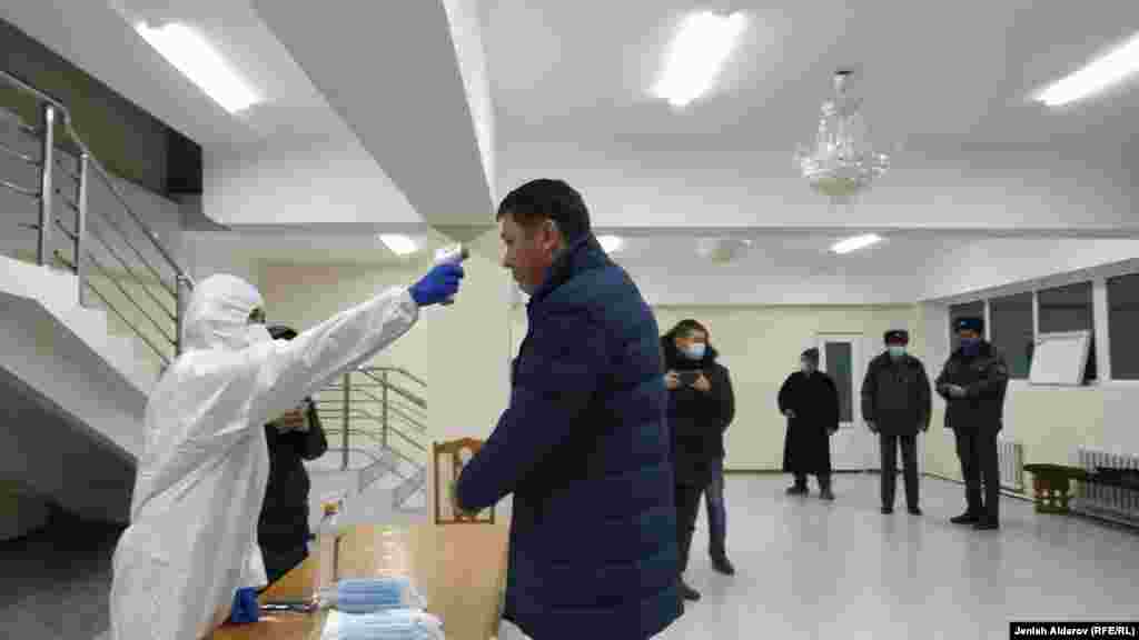 В некоторых избирательных участках члены комиссии одеты в спецодежду, проверяют температуру тела граждан