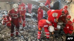 Pjesëtarë të Gjysmëhënës së Kuqe iraniane duke kërkuar nën rrënoja të një banese në Teheran pas sulmeve izraelite.
