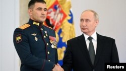 Președintele Rusiei, Vladimir Putin, dă mâna cu locotenent-colonelul Sultan Hașegulkov în timpul unei ceremonii de înmânare a decorațiilor „Steaua de Aur”, Moscova, 8 decembrie.
