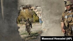 Afghan soldiers near a hole in a wall made to rescue people from the Shamshad TV building after a deadly attack in Kabul on November 7.