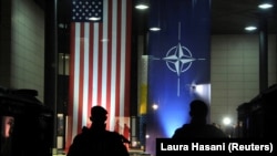 Ushtarët e Kosovës qëndrojnë pranë flamurit të SHBA-së dhe NATO-s. Prishtinë, 14 dhjetor, 2018.