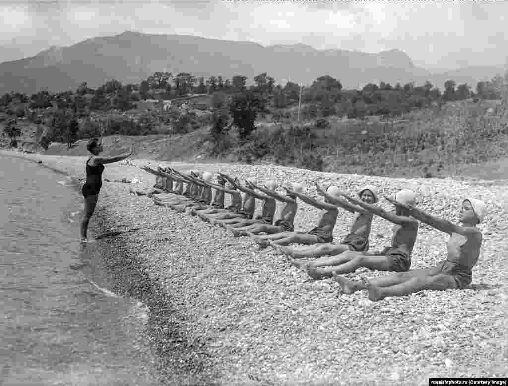 Деца правят упражнения на каменист плаж в "Артек" през 30-те години на миналия век.Лагерът скоро се разраства и се превръща в част от комунистическата младежка организация на Съветския съюз „Млади пионери“. Всяко лято в "Артек" се запазват места за деца с високи постижения, както и за наследниците на влиятелни членове на комунистическата партия.