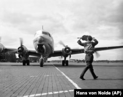 Американский военно-транспортный самолет C-54 Skymaster с грузом угля в аэропорту Темпельхоф в блокированном советской армией западном Берлине, 7 июля 1948 года