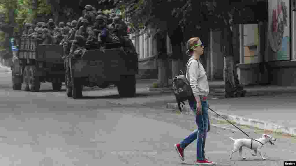 Stanovnica prelazi ulicu dok ukrajinska vojna vozila kreću na svoje pozicije. Grad Bahmut je pod intenzivnim granatiranjem ruske vojske.