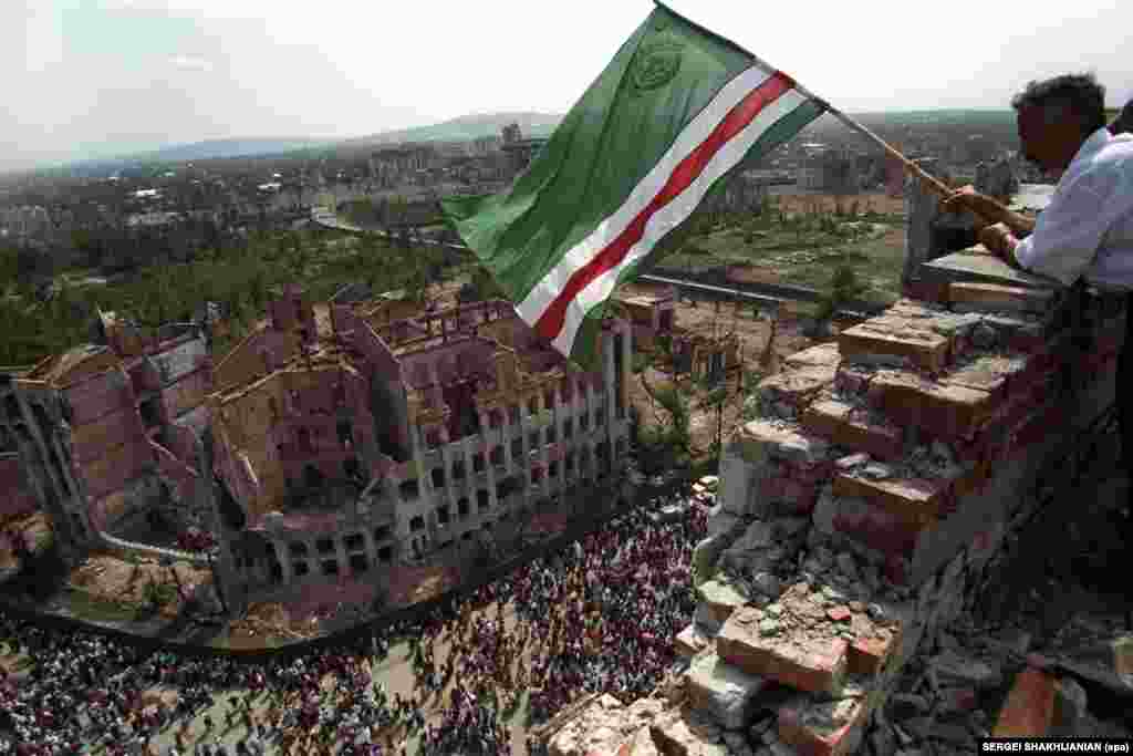 A man waving a separatist Chechen flag in Grozny, the region&rsquo;s capital, in 1995. Many buildings were destroyed by Russian bombs and other weaponry in the 1994-96 war between federal troops and Chechen rebels, which ended with de facto independence for Chechnya.