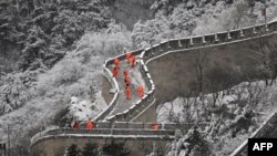 Radnici čiste led i snijeg na Kineskom zidu u Badalingu, sjeverno od Pekinga, nakon snježnih padavina tokom noći 15. decembra 2023.