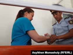 A policeman puts handcuffs on Sairagul Sauytbay, an ethnic Kazakh from China, in a trial in the Kazakh city of Zharkent in July 2018.