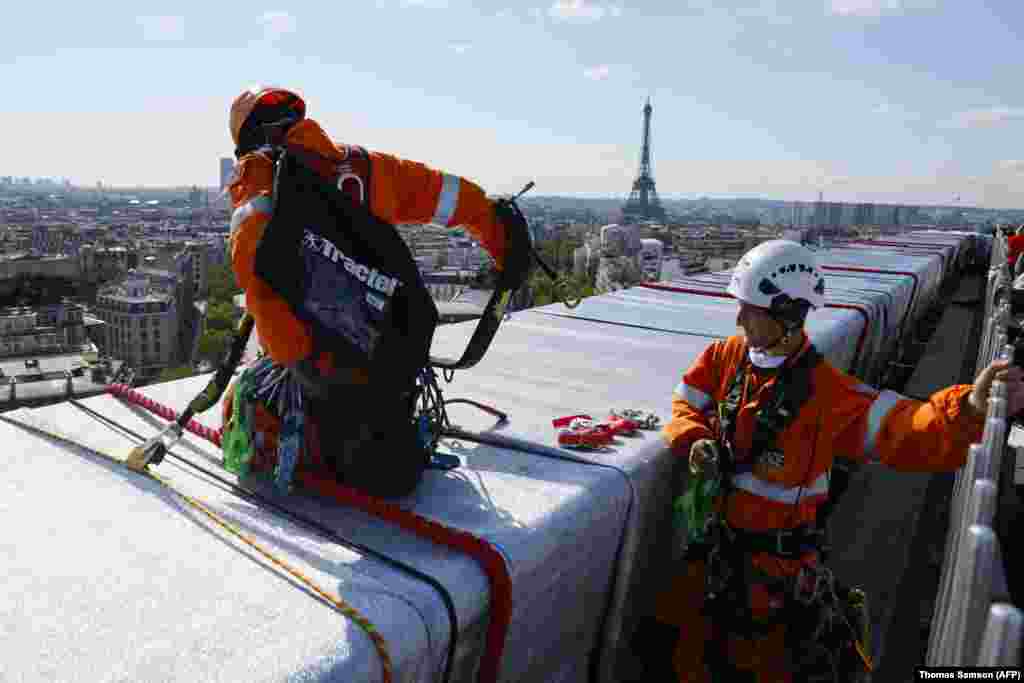 Vörös kötéllel rögzítik a szövetet a Diadalív tetején szeptember 16-án. A lepel legnagyobb tekercsei nyolc méter szélesek és egy tonnát nyomnak. Összesen 25 000 négyzetméternyi szövet alkotta a Diadalív leplét