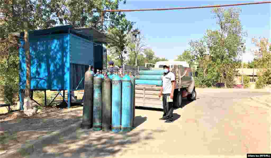 Мужчина загружает пустой кислородный баллон в машину возле больницы. Большинство пациентов центра не могут дышать самостоятельно, их подключат к специальным устройствам и кислородным баллонам