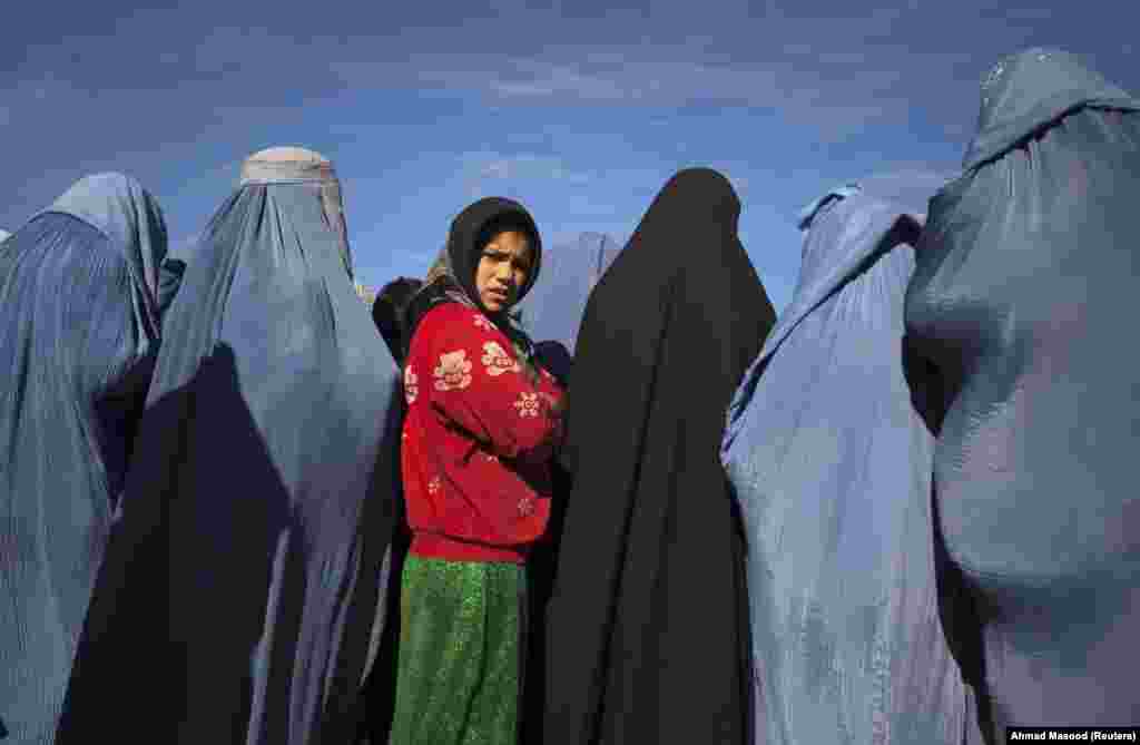 Девојче од Авганистан стои меѓу вдовици со бурки за време на проектот за вработување на хуманитарната организација &bdquo;КАРЕ Интернационал&ldquo;.
