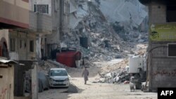Copii palestinieni se plimbă printre ruinele unui cartier rezidențial din sudul orașului Khan Yunis din Fâșia Gaza, la 5 iulie 2024.