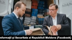 Șeful SIS, Alexandru Musteață (stânga), ținând în mână câteva dintre dosarele din perioada regimului totalitar care au fost desecretizate și transmise Agenției Naționale a Arhivelor.