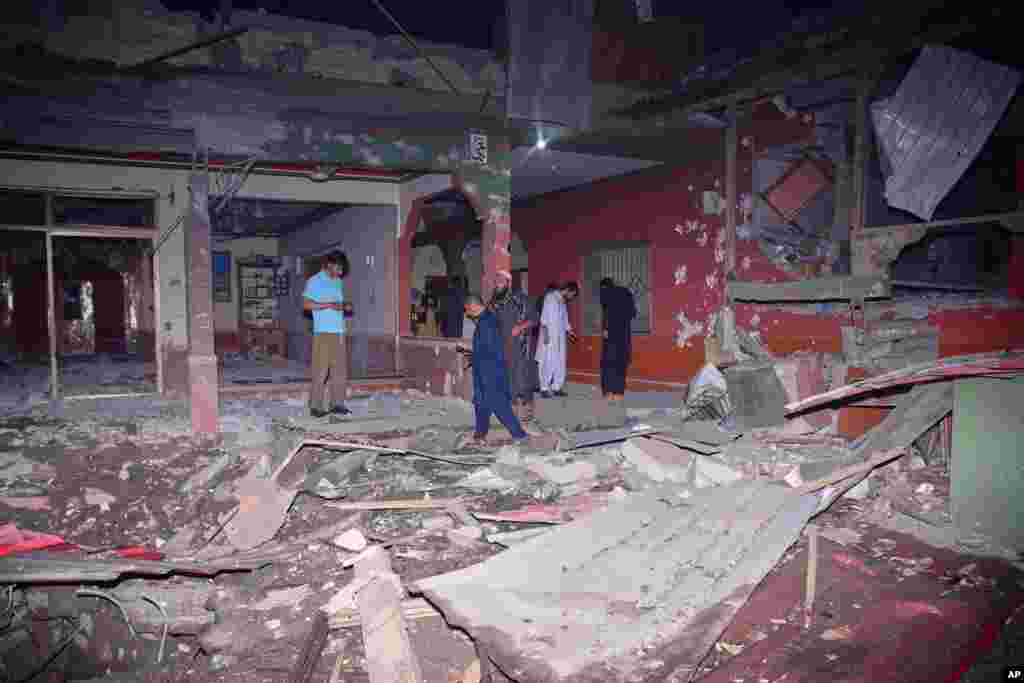 Локални жители и новинари пред зграда оштетена од индиски ракетен напад во близина на Музафарабад, главниот град на пакистанскиот контролиран Кашмир