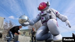 Работници инсталират надуваем космонавт на площад в черноморския пристанищен град Евпатория на окупирания от Русия полуостров Крим по случай Деня на космонавтиката - 12 април. Тогава се отбелязва годишнината от историческия първи космически полет на Юрий Гагарин през 1961 г.