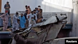 People stand next to the debris of a plane after crashed in a residential area near an airport in the southern seaport city of Karachi on May 22.