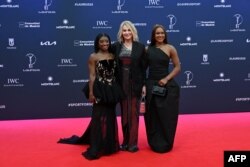 Симон Байлс (вляво) и Ребека Андраде (вдясно) позират заедно с румънската легендарна гимнастичка Надя Команечи на червения килим преди връчването на наградите "Лауреус" в Мадрид, 21 април 2025 г.