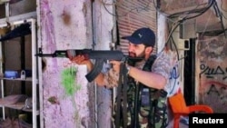 Iranian religious singer Hamid Reza Alimi points a rifle while on a trip to Syria.