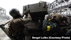 Украинские солдаты загружают тело танкиста, погибшего под обстрелом в районе Донецкого аэропорта. 19 октября 2014 года.