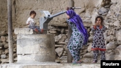 FILE: A young girl pumps water from a well in the village of Manugay in the Pech Valley.