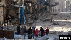 Люди в Сирии посреди разрушенных зданий.