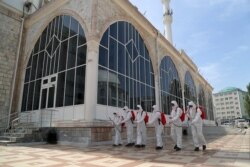 Disa punëtorë dezinfektojnë një xhami në Dagestan.
