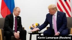 Președintele american Donald Trump (dreapta) gesticulează în timpul unei întâlniri cu președintele rus Vladimir Putin la un summit al liderilor G20 în iunie 2019.