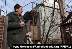 дядя Вася держит в руках осколки от снарядов