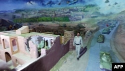 Сотрудник афганского музея идет рядом с экспонатами, изображающими войну афганцев против СССР. Герат, 27 апреля 2012 года.